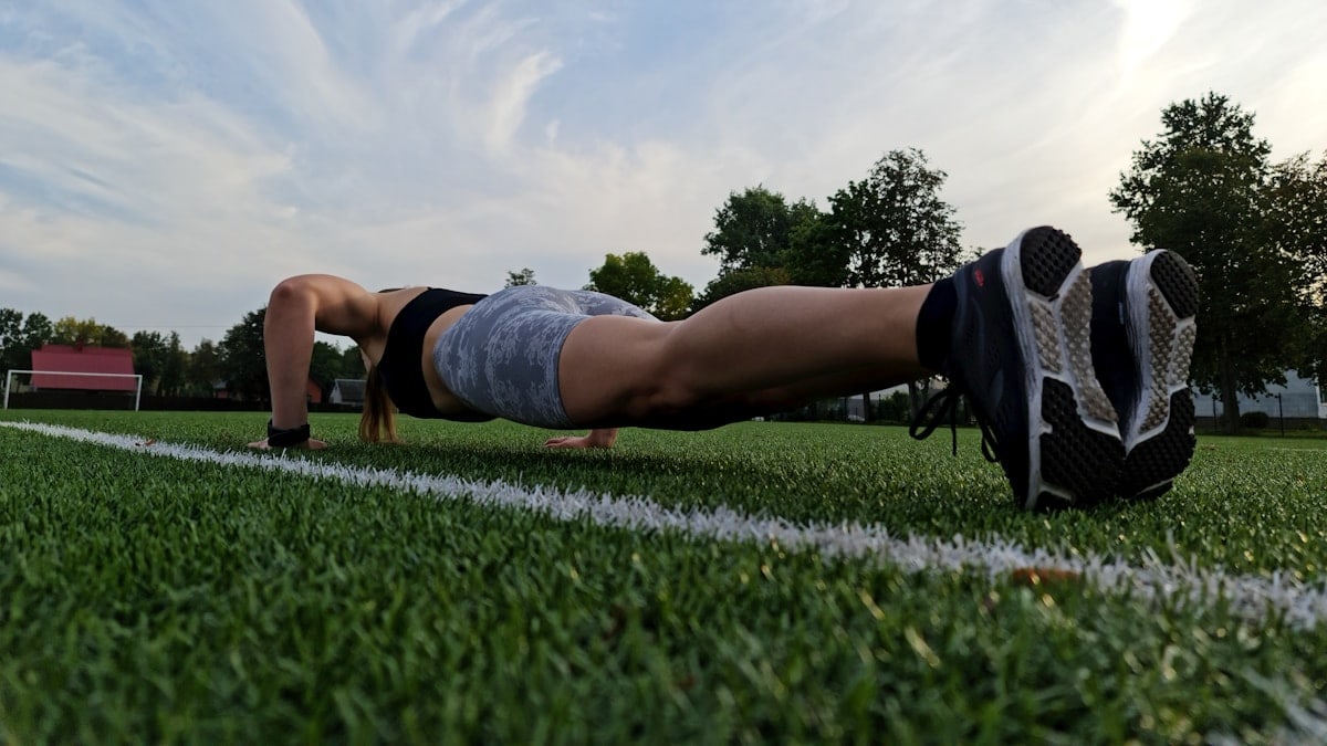 a woman is doing push ups on the grass
